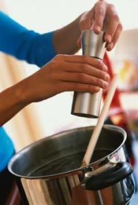 Adding cracked pepper to a pot of broth
