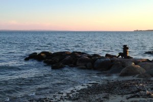 Woman eats her dinner on rocks at Falmouth Harbor